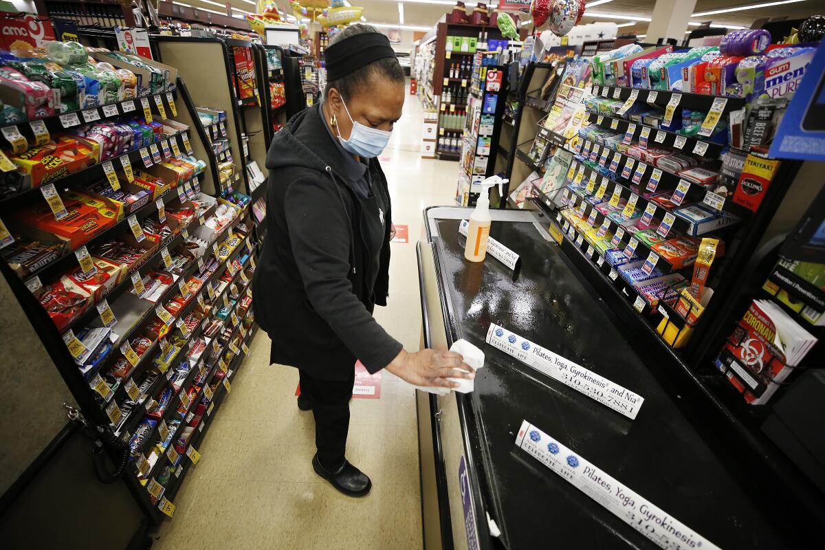 Vons checker cashier Miyoshi Lampkin, who has worked at Vons for 40 years, cleans and sanitizes her checkout lane.