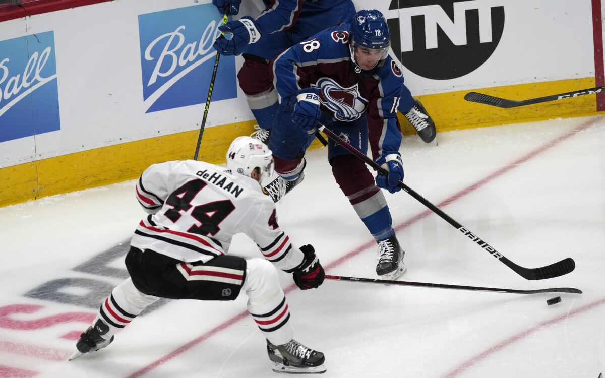 Colorado Avalanche center Alex Newhook, back, passes the puck as Chicago Blackhawks defenseman Calvin de Haan covers in the first period of an NHL hockey game Wednesday, Oct. 13, 2021, in Denver. (AP Photo/David Zalubowski)