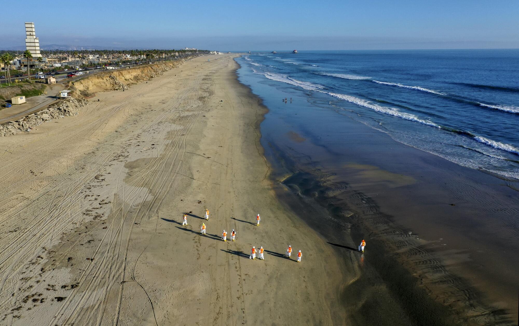 Cleanup workers are seen in an aerial view of a stretch of soiled beach