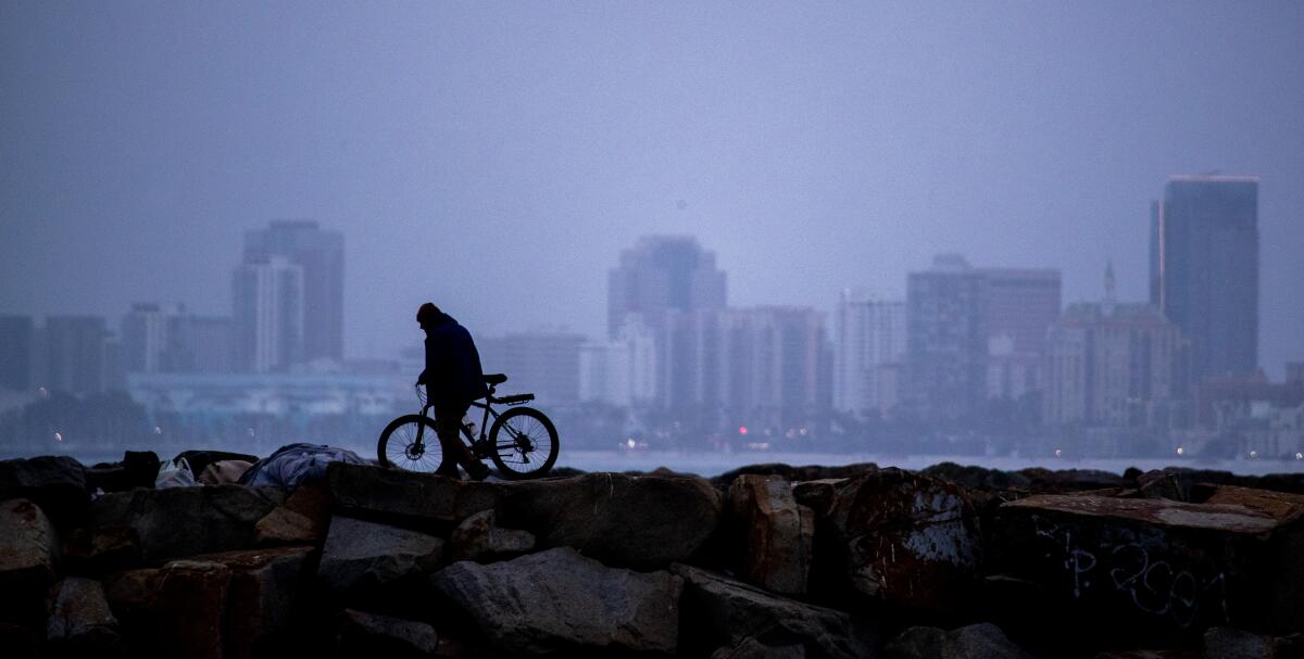 Looking out at downtown Long Beach from a path a silhouetted bicyclist rides on.