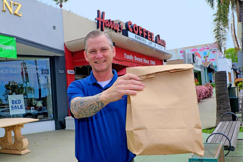 Harry's Coffee Shop manager Tom Frankenberger has an order ready for curbside pickup at the La Jolla diner. He said some of the local hangout's longtime customers still stop by for takeout, but San Diego County's emergency regulations not allowing onsite dining - to help stop the spread of coronavirus - has put a major dent in business.