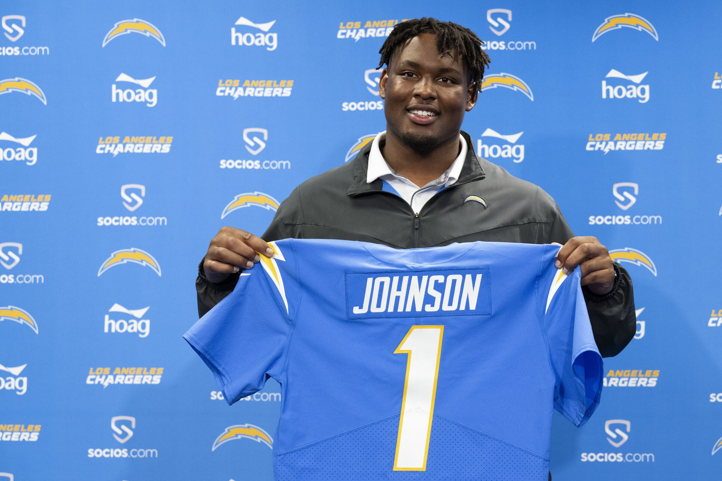 First-round NFL football pick Zion Johnson poses for a photo with a Chargers jersey. 