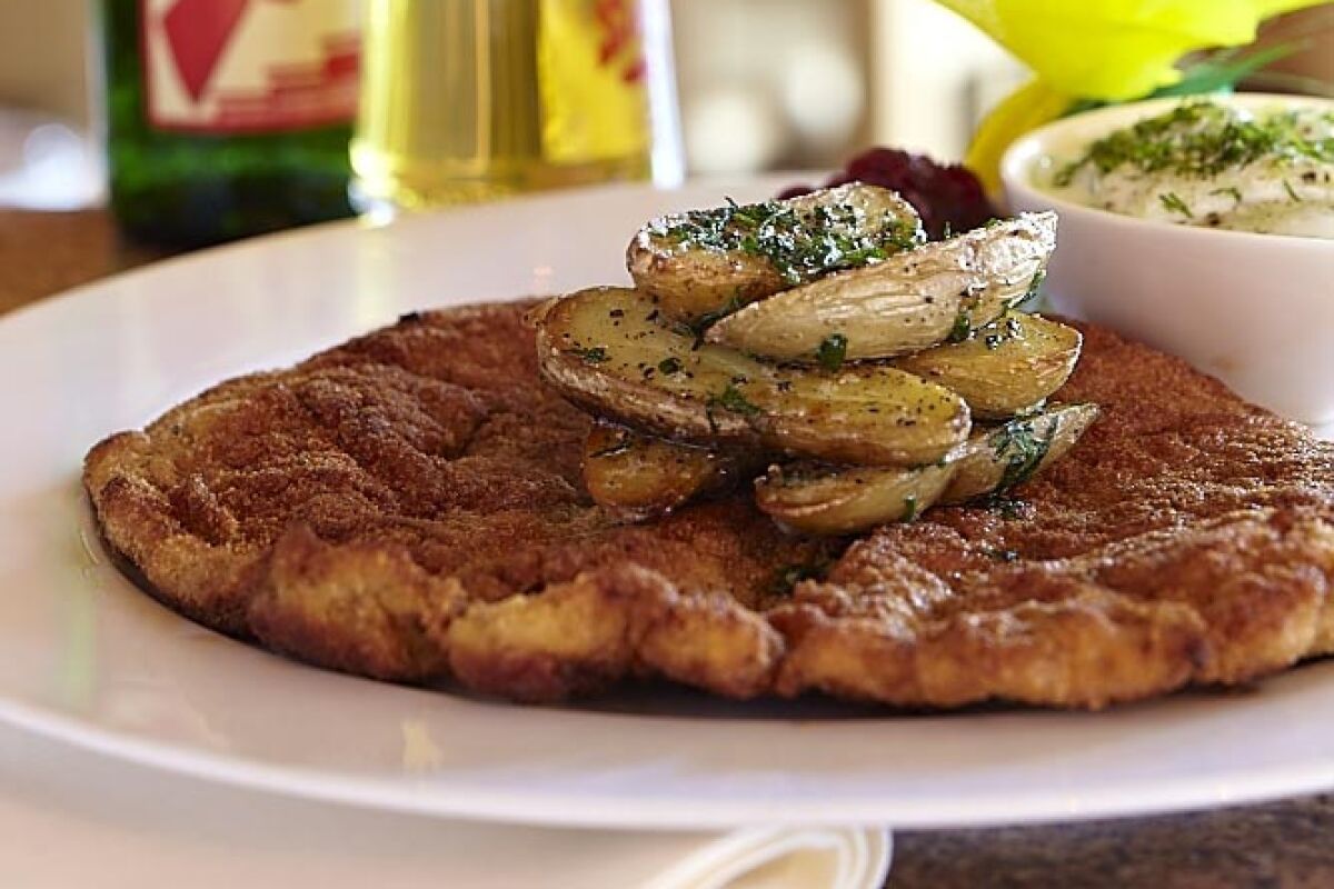 Weiner schnitzel on a plate next to a bottle and glass of beer