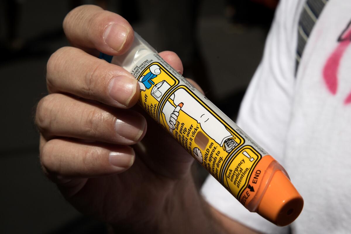 A protester holds up an EpiPen for reporters during a gathering outside the office of hedge fund manager John Paulson on Aug. 30, 2016 in New York City. Paulson's hedge fund is a major investor in Mylan, the pharmaceutical company who has raised the price of EpiPens over 400 percent in the past 8 years.