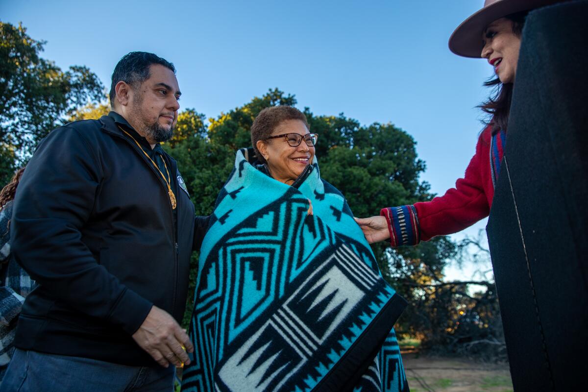 L.A. Mayor Karen Bass wears a shawl presented by Rudy Ortega and Cynthia Ruiz at a winter solstice ceremony.