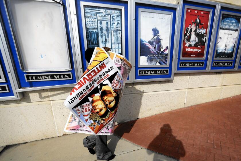 A poster for “The Interview” is carried away by a worker after being pulled from a display case Wednesday at a Carmike Cinemas movie theater in Atlanta.