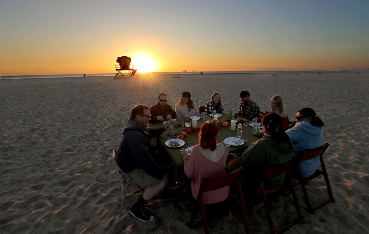 A group eats at a table set up on the beach.