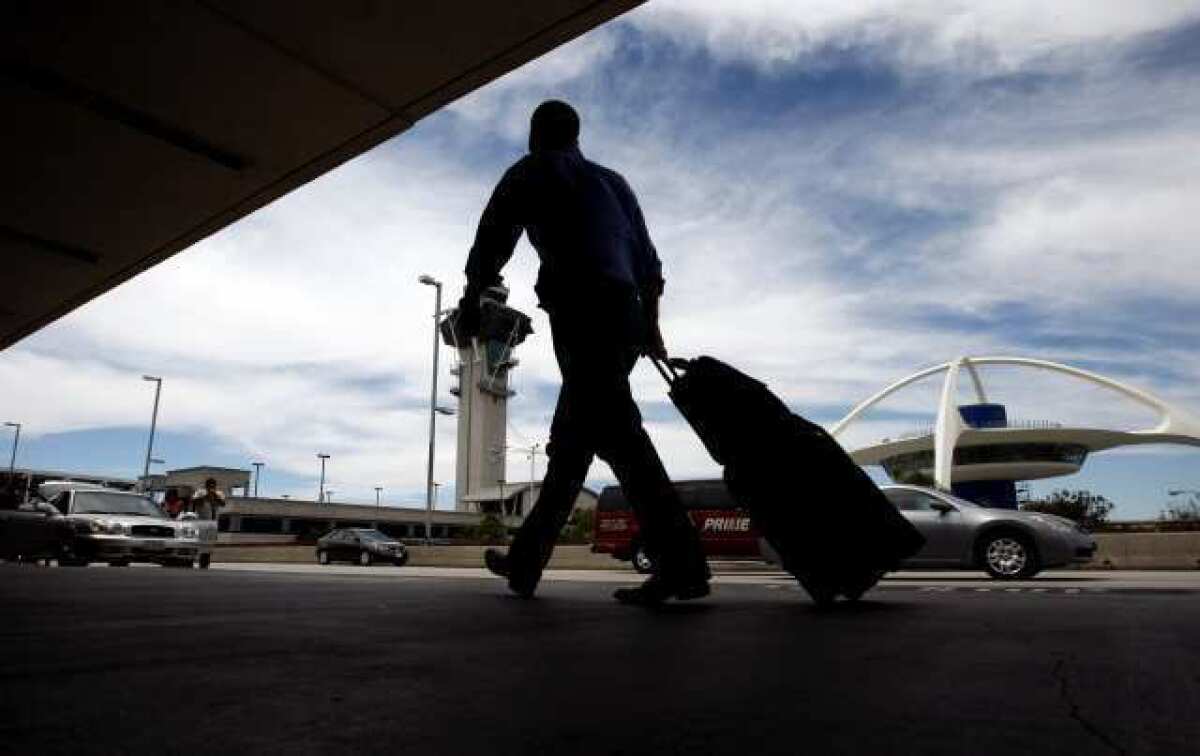 A traveler totes luggage as he makes his way down the sidewalk at Los Angeles International Airport. Airlines lowered some fares when they adopted bag fees but not enough to offset the new charges, a new study finds.