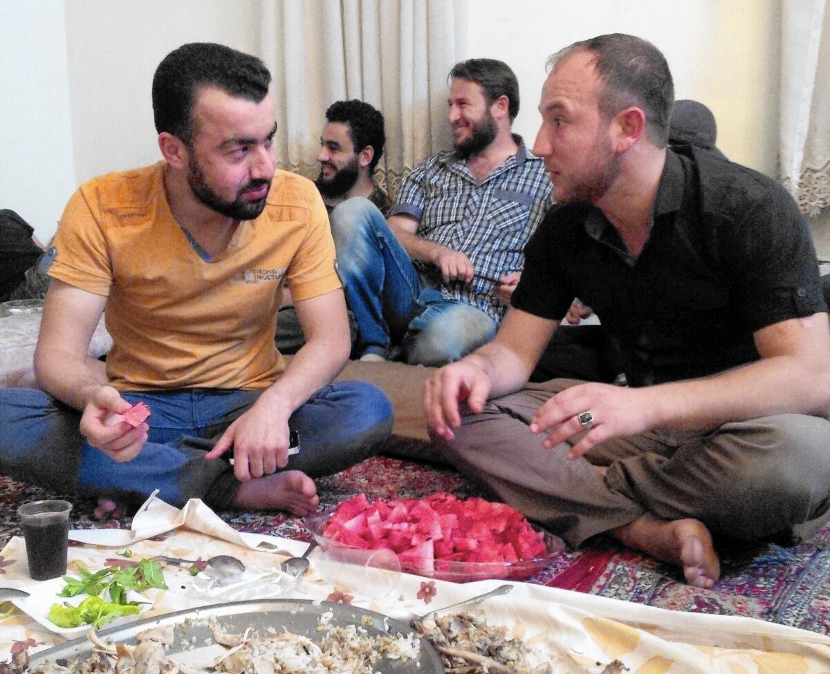 Abdulkareem Laila, left, better known as Abu Firas, a spokesman for the Syrian rebel group Islamic Front, shares a meal with rebel fighter Omar Hamoude in Aleppo.