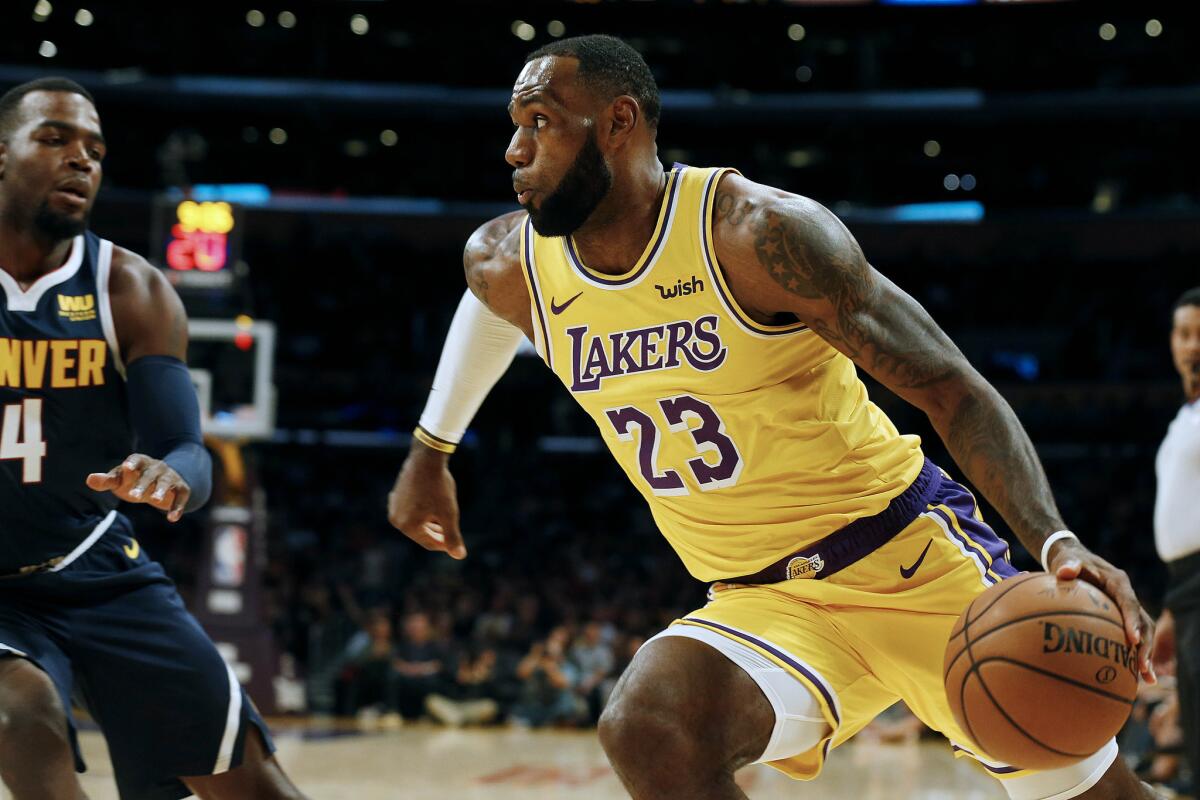 Lakers forward LeBron James drives the baseline against Nuggets forward Paul Millsap during a preseason game at Staples Center.