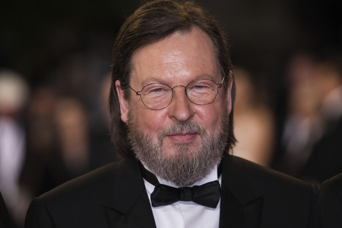 A man with shoulder-length hair and a beard wearing a tuxedo at a film premiere
