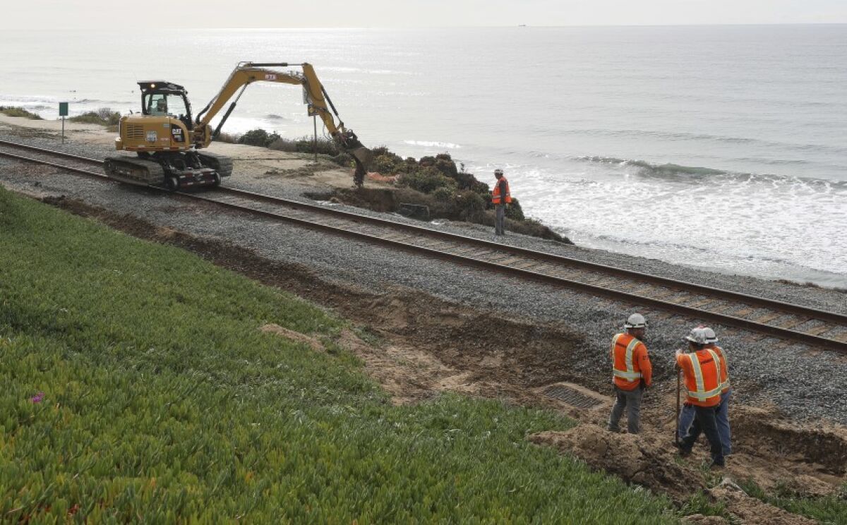 Workers on Saturday, Nov. 30, repair an area next to the railroad tracks in Del Mar that washed out during last week’s storm.