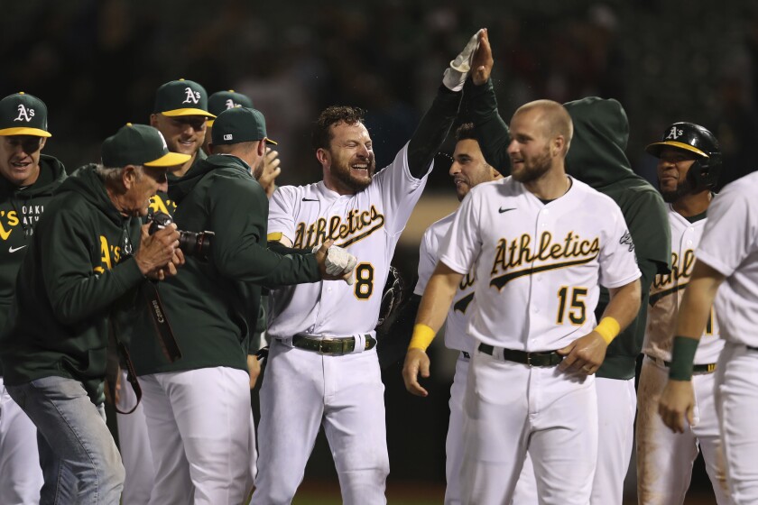 Oakland Athletics' Jed Lowrie (8) is congratulated by teammates after hitting the game-winning home run against the Cleveland Indians during the ninth inning of a baseball game in Oakland, Calif., Friday, July 16, 2021. (AP Photo/Jed Jacobsohn)