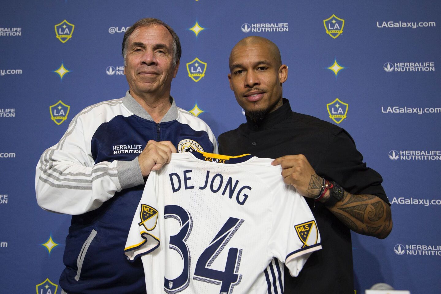 LA Galaxy Head Coach and General Manager Bruce Arena (L) and Midfielder Nigel de Jong hold his new jersey up for members of the press as the newest signed player for the LA Galaxy soccer team at the StubHub Center, February 16, 2016 in Carson, California. De Jong represented the Dutch at the FIFA World Cup in 2010 and 2014 and helped his country qualify in 2006 before an injury kept him out of the tournament. / AFP / David McNewDAVID MCNEW/AFP/Getty Images ** OUTS - ELSENT, FPG, CM - OUTS * NM, PH, VA if sourced by CT, LA or MoD **