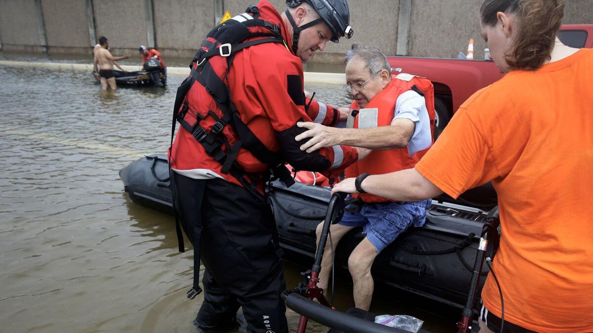Crews helps Frank Andrews, 74, into his walking chair after rescuing him from his flooded home in the Braeswood Place neighborhood, Southwest of Houston.