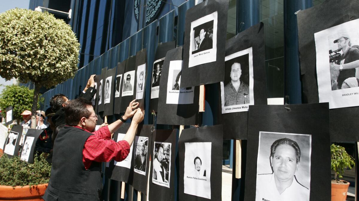 A man hangs photos of slain journalists during a protest at the gates of the Attorney General's Office in Mexico City in 2007.