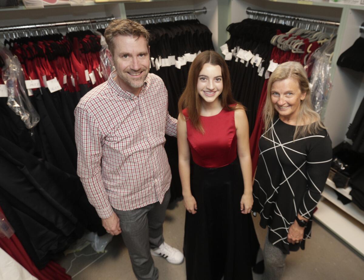 LCHS Choral Director Dr. Jeffrey Brookey, senior Maya Morgan, and Choral Parents Assn. Co-President Leslie Lowes display a new Women's Ensemble gown that allowed the school to donate 133 dresses it no longer needed to a Valencia school.