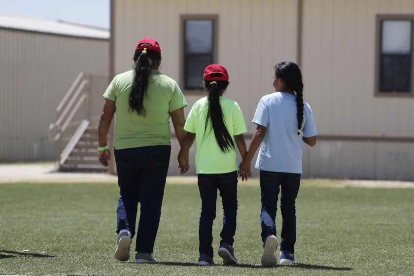 Immigrants seeking asylum hold hands as they leave a cafeteria at the ICE South Texas Family Residential Center, Friday, Aug. 23, 2019, in Dilley, Texas. U.S. Immigration and Customs Enforcement hosted a media tour of the center that houses families who are pending disposition of their immigration cases.(AP Photo/Eric Gay)