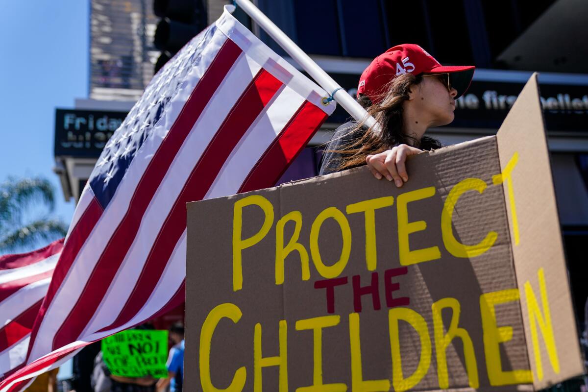 A QAnon supporter protests at the CNN building with sign that says 'Protect the Children'