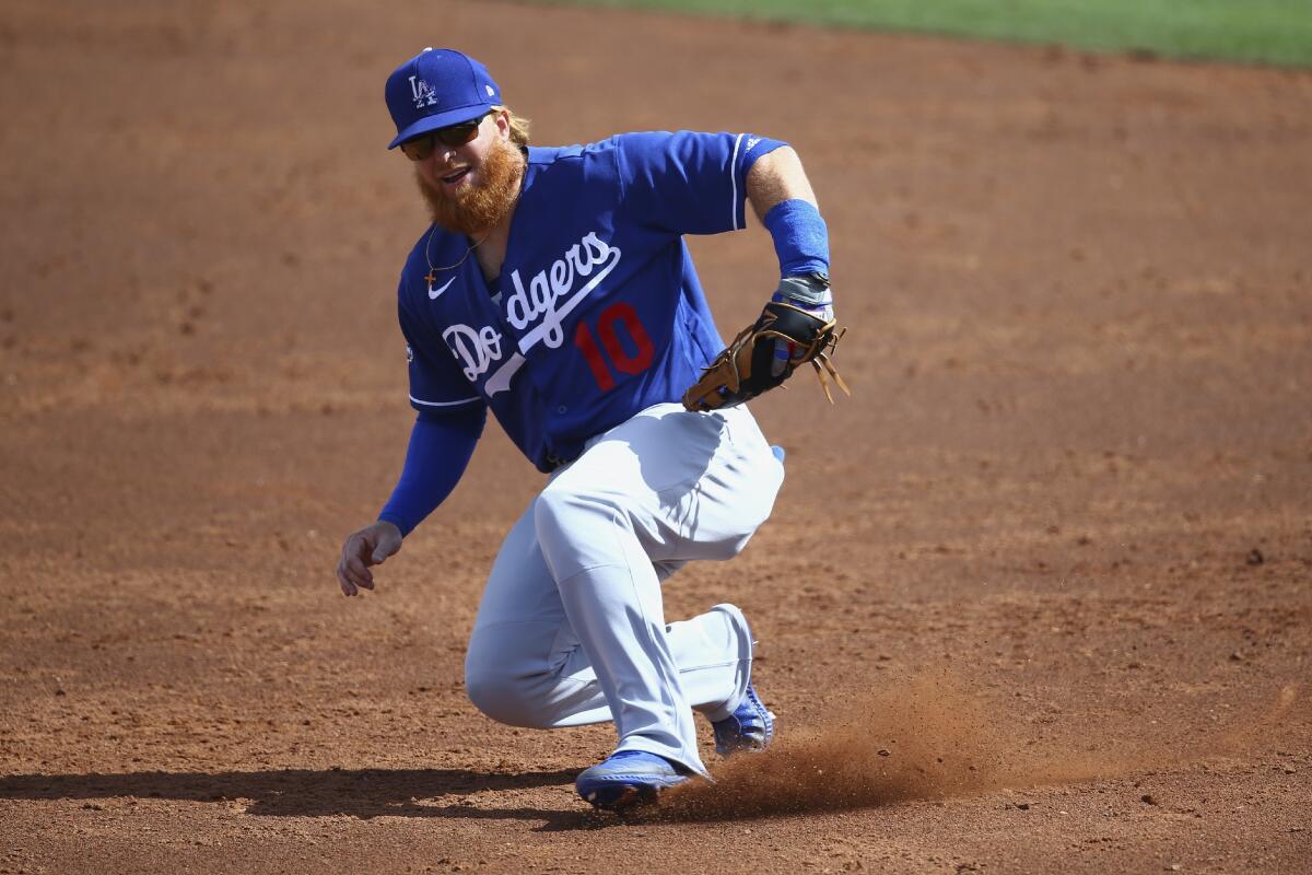 Dodgers third baseman Justin Turner slides over in an attempt to field a grounder against the Cincinnati Reds during a spring training game Monday in Arizona.