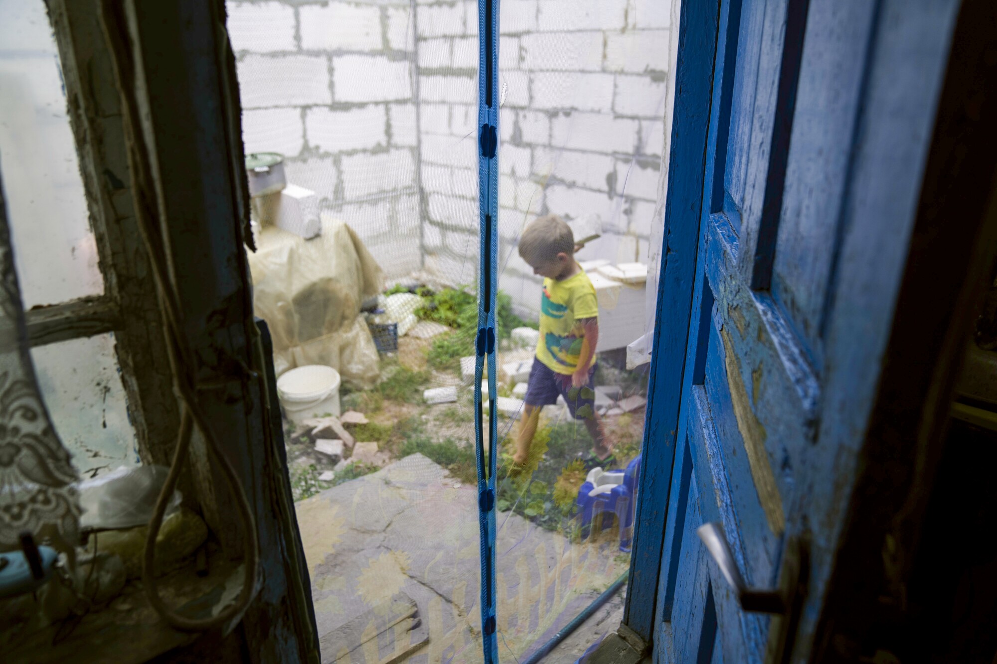 A boy appears in the yard through the door.
