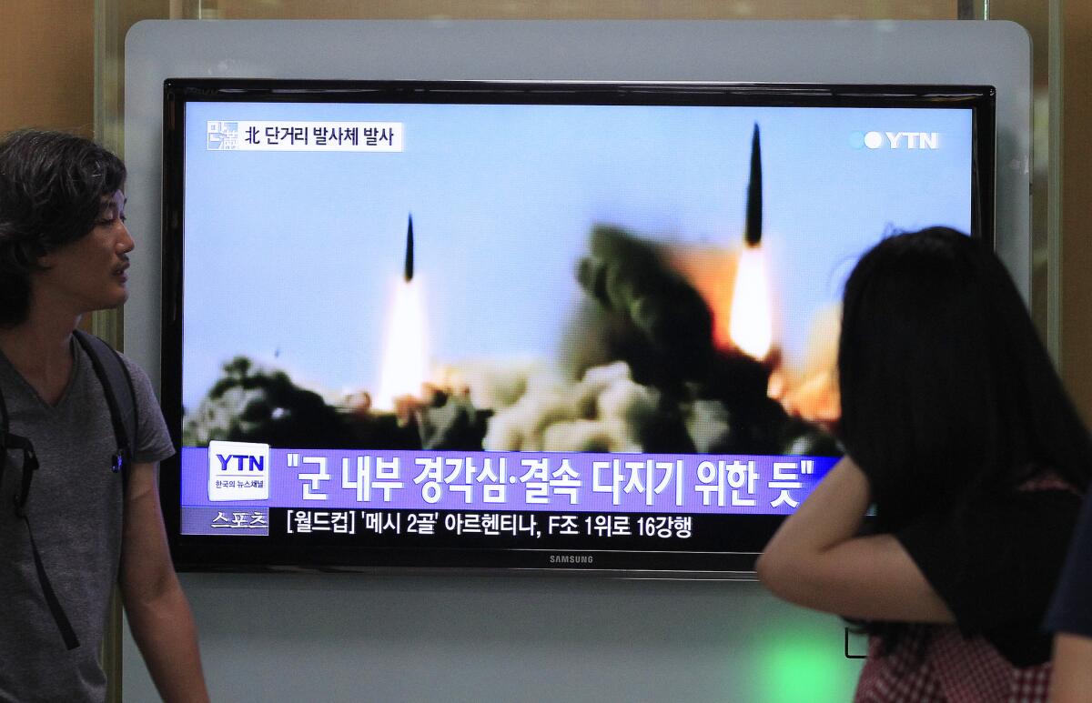 People at a Seoul rail station watch a TV news program showing a missile launch conducted by North Korea on Thursday.