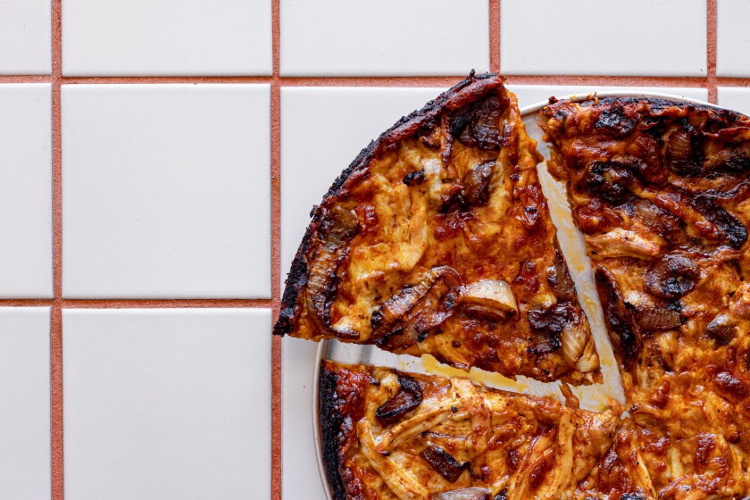 Overhead shot of a slice of pizza next to a pizza pie 