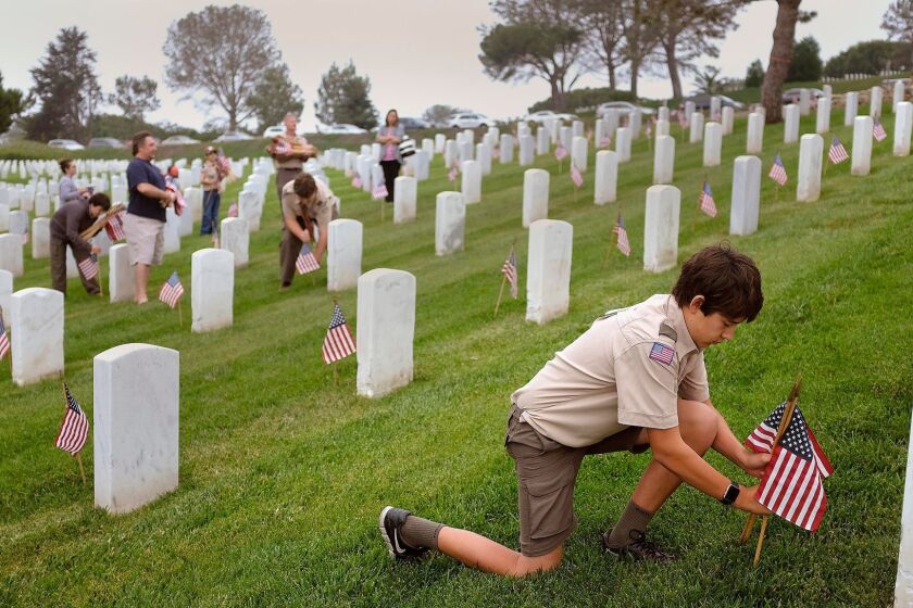 SAN DIEGO_|Cub Scouts and Boy Scouts from around the county placed American flags in the grass by markers of those who died for their country at Fort Rosecrans National Cemetery as part of an annual service project at the cemetery. |Star Scout Steven Seibert places a flag next to a gravemarker two days before Memorial Day.|John Gastaldo/San Diego Union-Tribune
