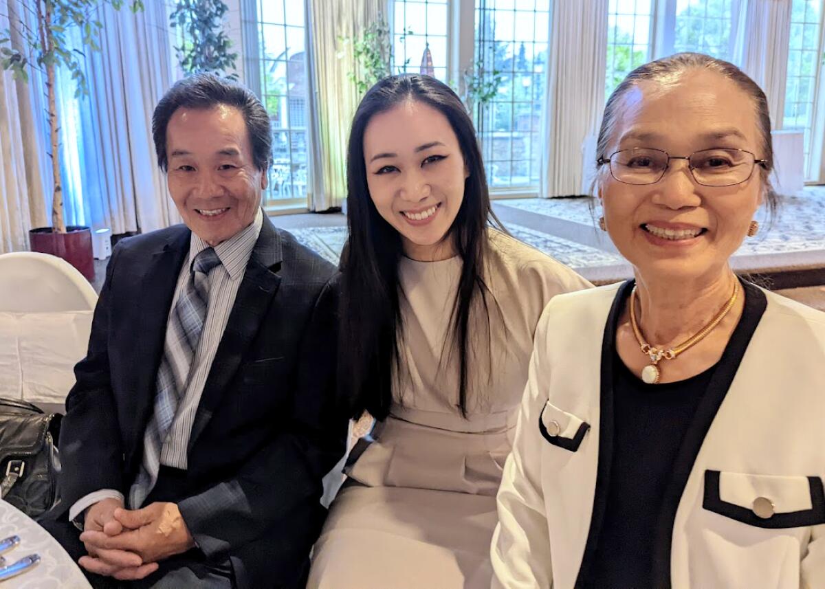 A father, daughter and mother smile for a photo.