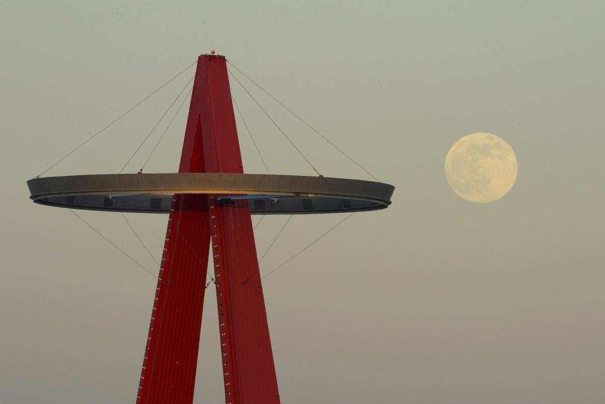The moon rises next the Los Angeles Angels' Big A sign.