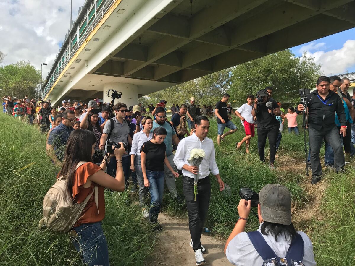 Julián Castro prepares to place flowers at crosses on the Rio Grande honoring migrants