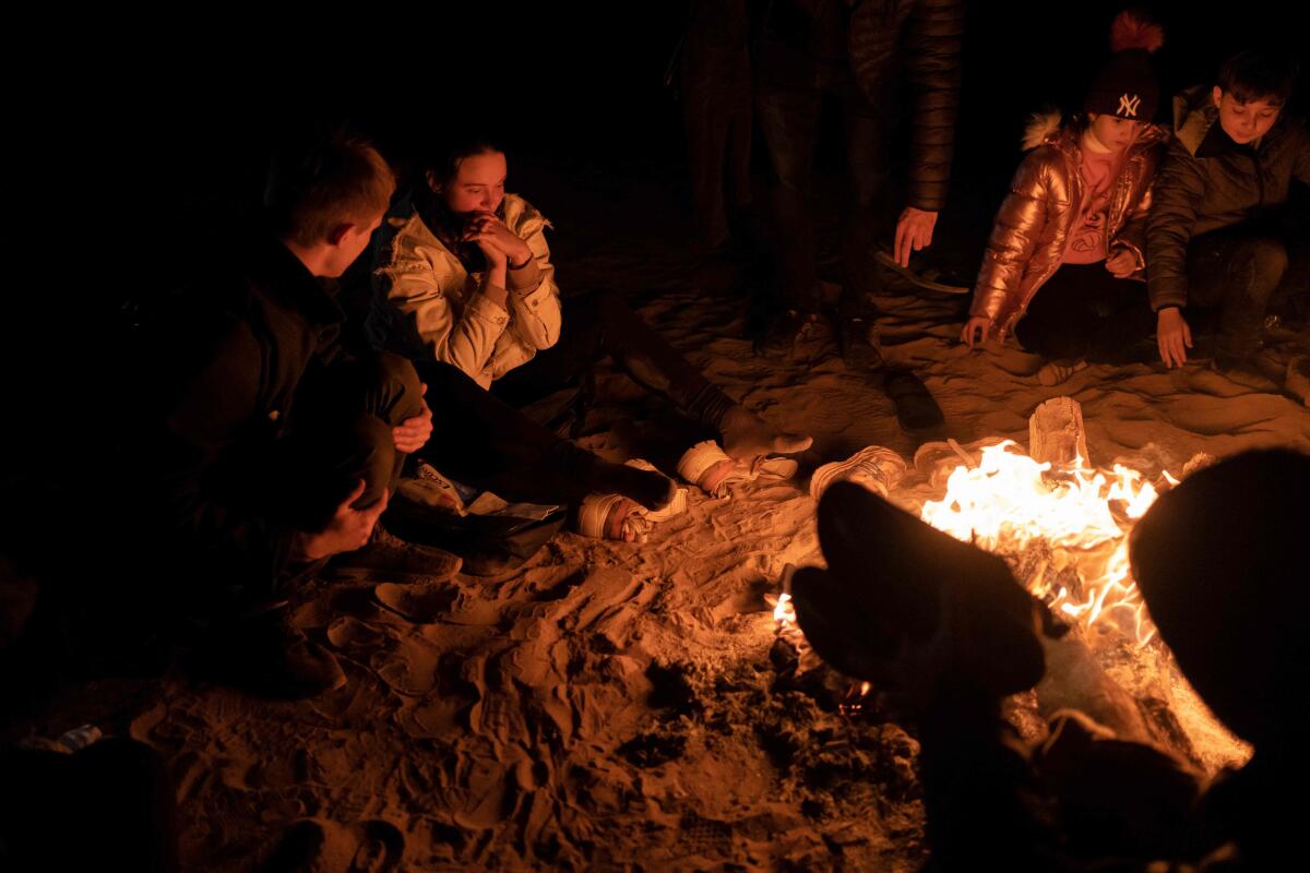 People sit around a small fire at night 