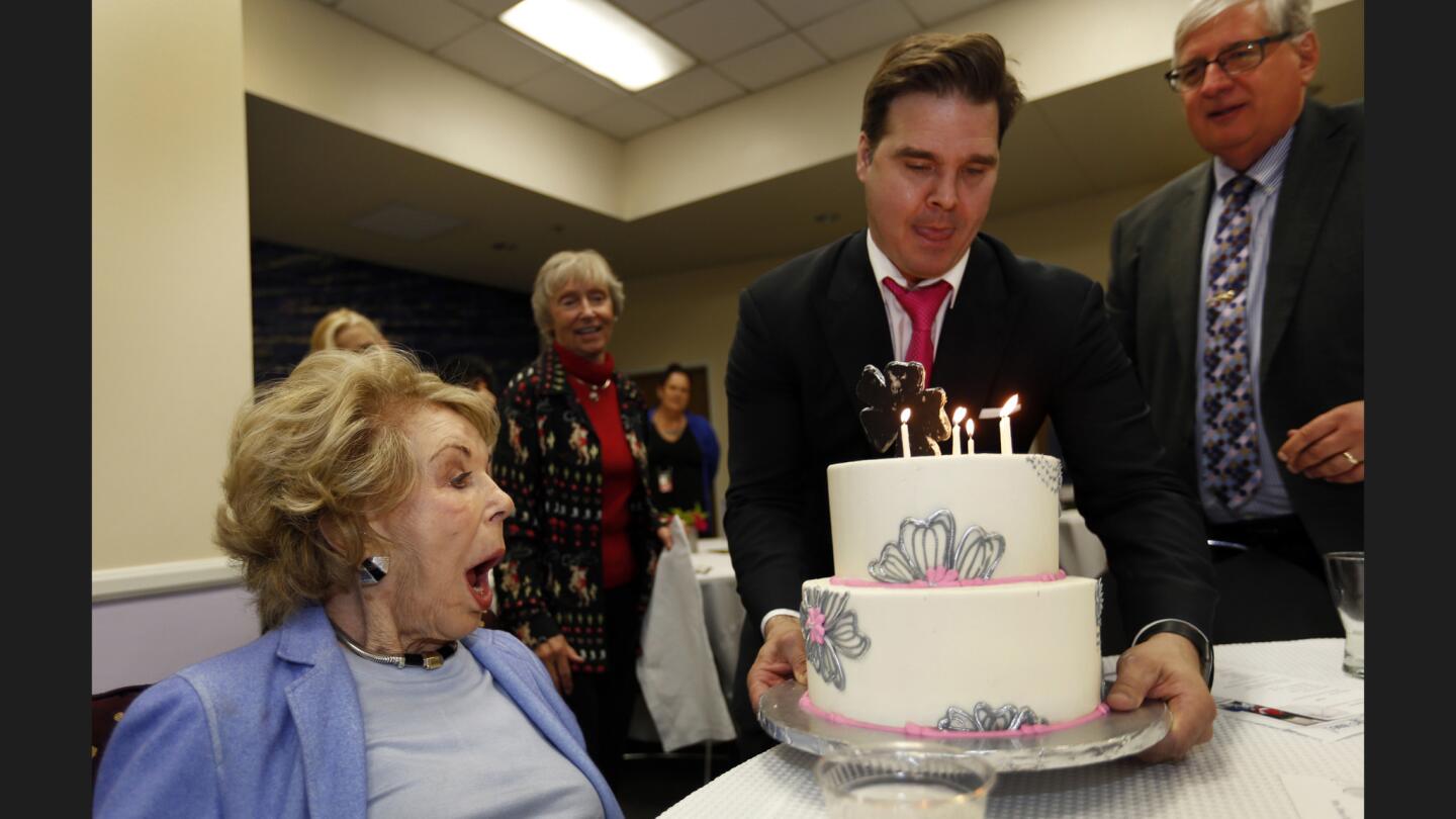 Anne Douglas, left, shows her surprise as Ivan Klassen and Herb Smith of the Los Angeles Mission deliver a cake at her birthday lunch at the mission's Anne Douglas Center for Women.