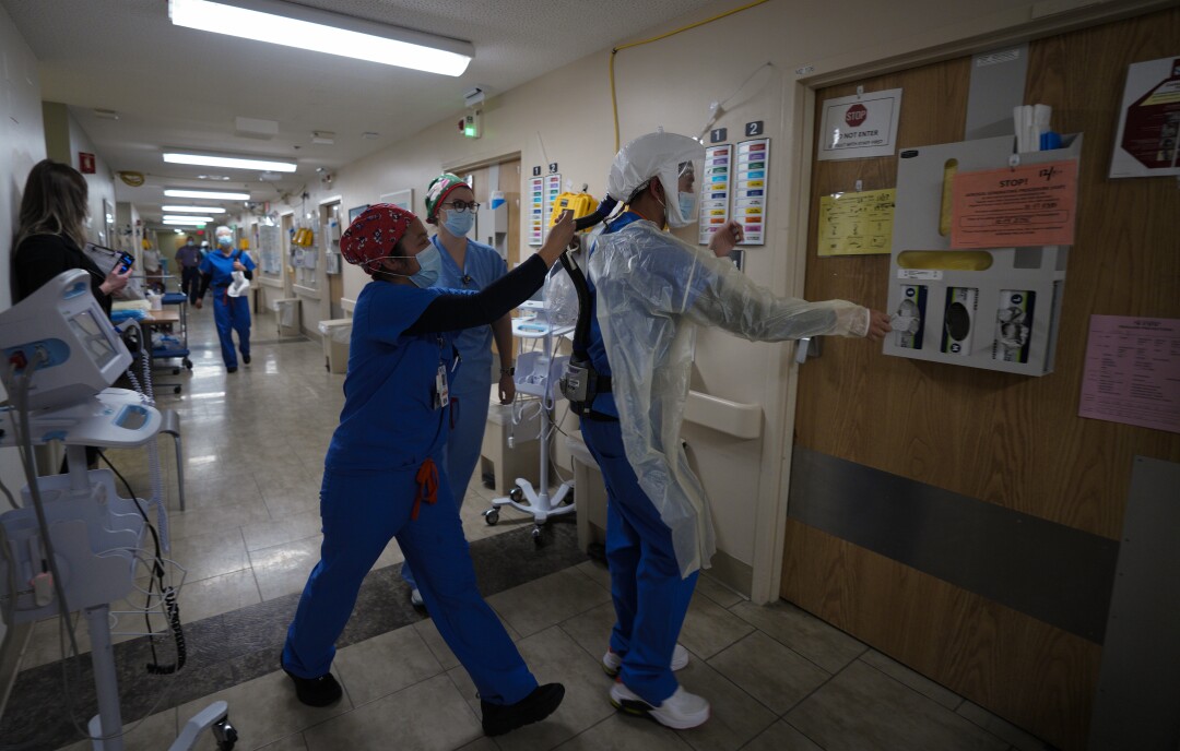 At Sharp Grossmont Hospital on Thursday, nurses in the COVID unit respond to an alarm sounding in a patient's room.