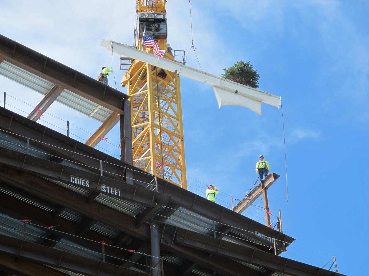 On June 6, iron workers guide the final steel beam into place at the site of the Clinical Sciences Center under construction by Roswell Park Cancer Institute in Buffalo, N.Y. The project is among more than $4.4 billion worth of development announced in the former Rust Belt city since 2012, bolstering hope for an economic recovery.