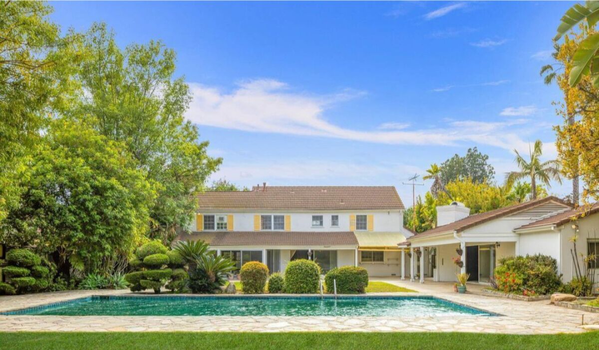 A pool behind a white house