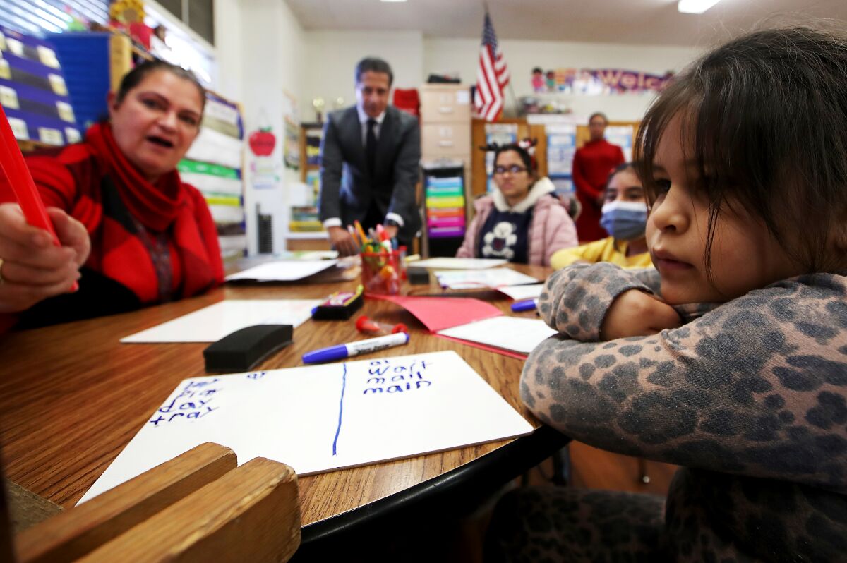 A student leans on a table as a teacher points out sentences to read.