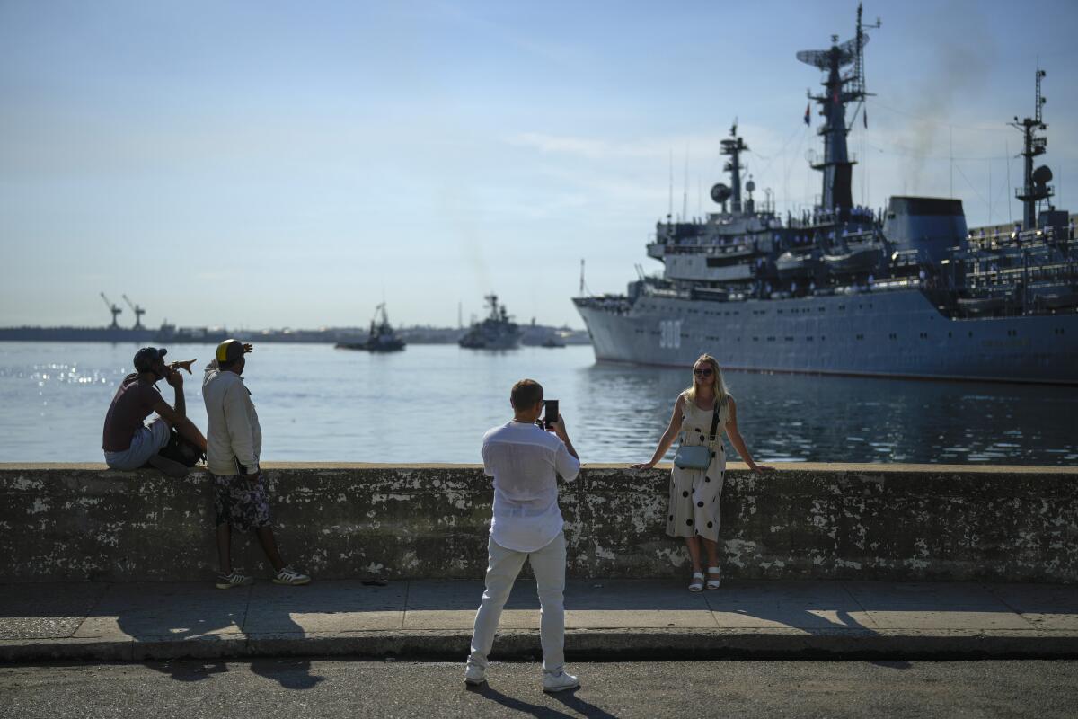 A woman poses for a photo before a Russian ship in Havana Bay. 