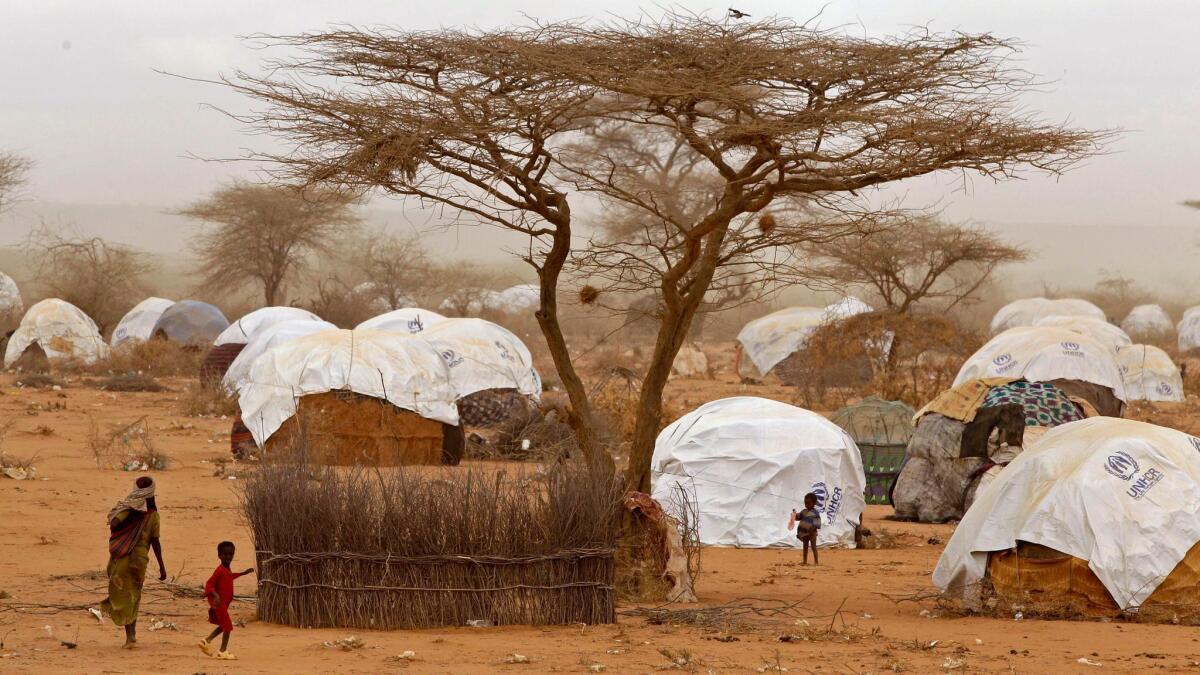 In this Aug. 4, 2011, photo, refugees walk among homes at a refugee camp in Dadaab, Kenya.