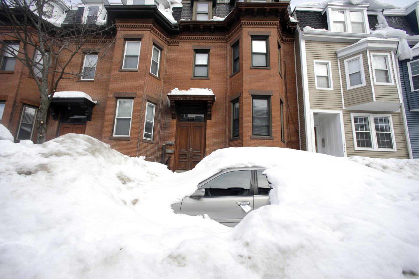 A car is buried in snow on a residential street in South Boston on Feb. 23.