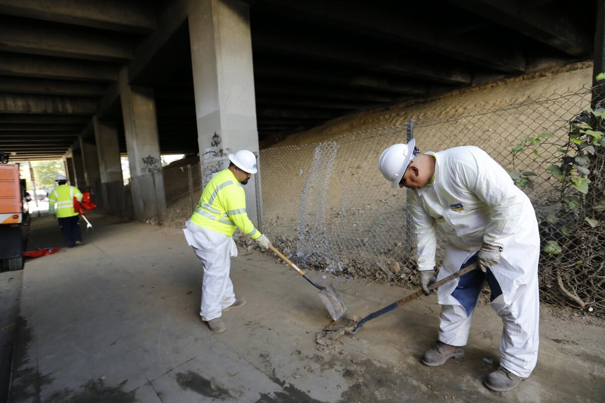 Caltrans workers clean up and remove debris from a tented homeless community under the 101 Freeway on March 14.