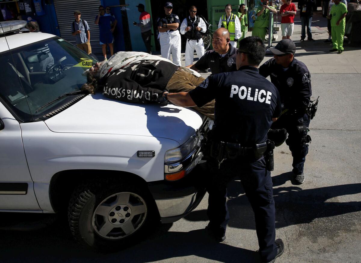 LAPD officers speak with David Busch before he is arrested for sitting on top of a sanitation truck in protest of a Venice Beach cleanup of homeless people's belongings.