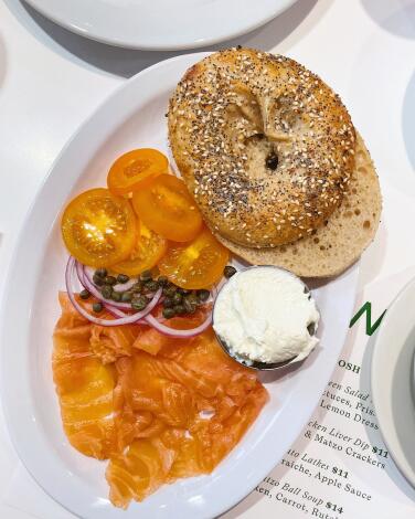 An overhead of an everything bagel with a lox plate featuring cream cheese, tomatoes, capers and onions at Hot Water Bagels