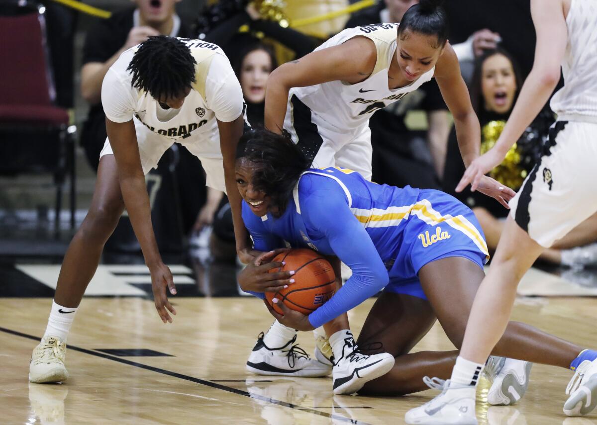 UCLA forward Michaela Onyenwere grabs a loose ball in front of Colorado guards Mya Hollingshed, back, and Quinessa Caylao-Do, left, during a game Jan 12.