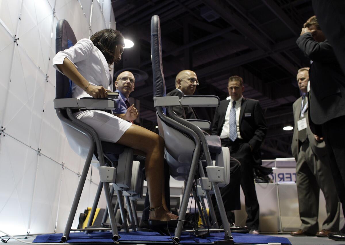 Vendors and exhibitors at the 2010 Aircraft Interior Expo at the Long Beach Convention Center try out seats designed with only 23 inches of space between them. A petition calls for minimum airline seat standards for legroom and width.