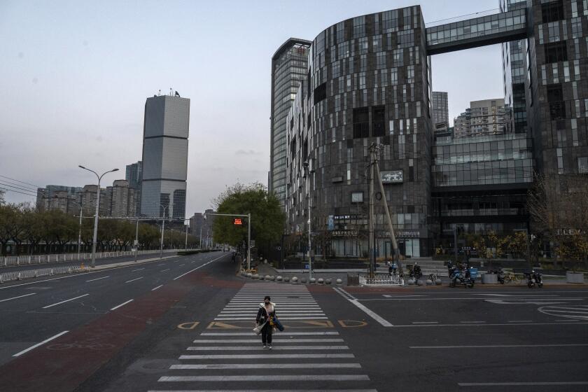 BEIJING, CHINA - NOVEMBER 22: A woman crosses a nearly empty road in the Central Business District during rush hour, after most workers were expected to work from home and offices closed, on November 22, 2022 in Beijing, China. In an effort to try to bring rising cases under control, the local government on Friday closed many restaurants for inside dining, switched schools to online studies, and asked people to work from home. Though the government recently revised its COVID strategy, it has said it will continue to stick to its strict zero tolerance policy with mandatory testings, quarantines and lockdowns in many areas in an effort to control the spread of the virus. (Photo by Kevin Frayer/Getty Images)