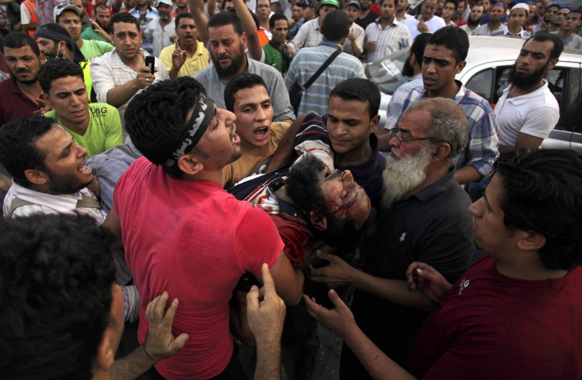 Supporters of Egypt's ousted President Mohamed Morsi carry an injured man to a field hospital after clashes with security forces in a Cairo neighborhood where pro-Morsi protesters have been holding a sit-in.