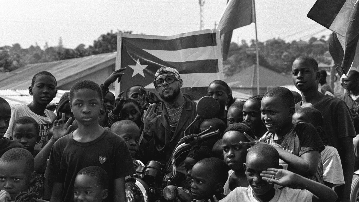 Rafa Pab?n posing with kids from an African village in front of a Puerto Rican flag.