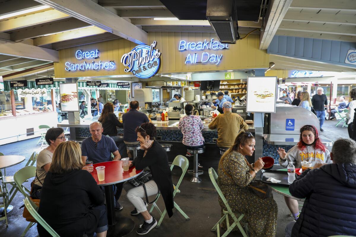 A lunch crowd at Phil's Deli & Grill, seated at outdoor tables under a beamed roof