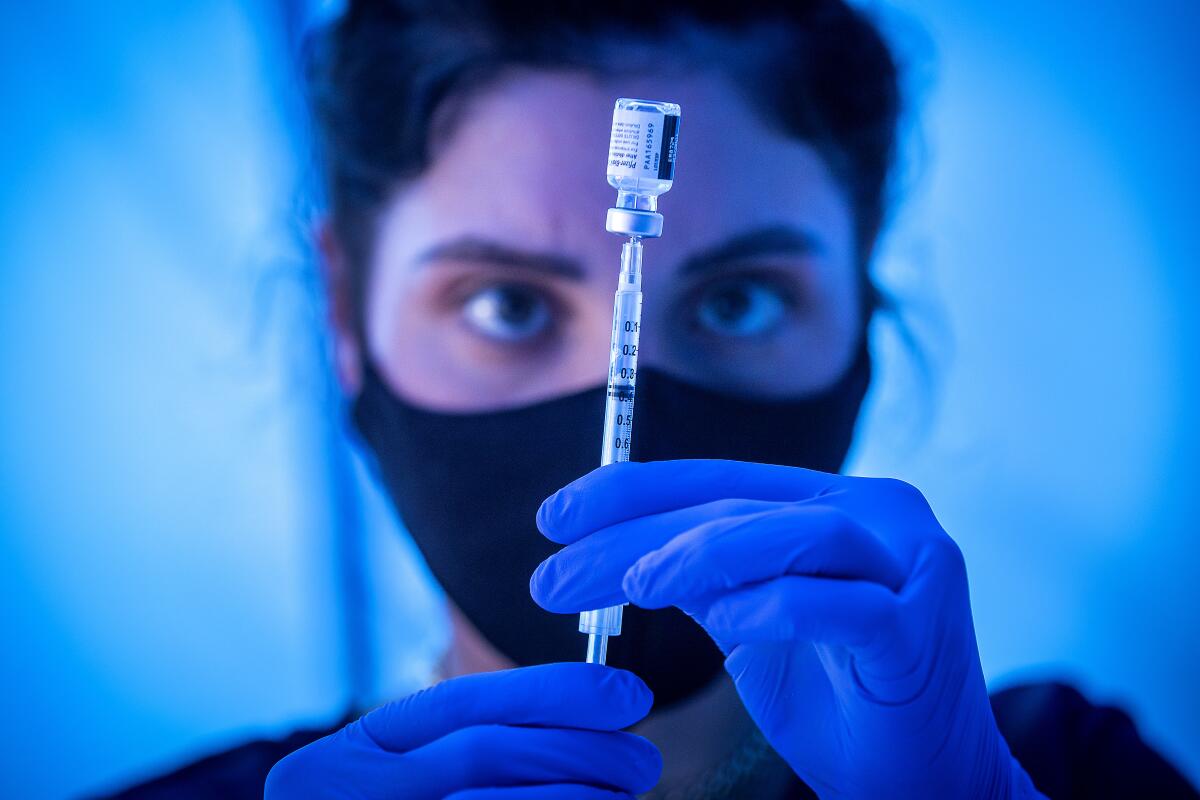 A medical student from Dartmouth University loads a syringe with Pfizer COVID-19 vaccine